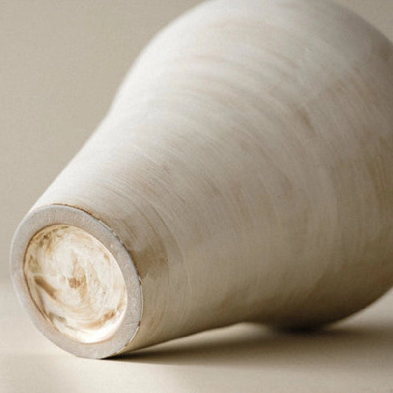 Close up of a handmade cream ceramic vase, with a round shape and a visible textured surface.