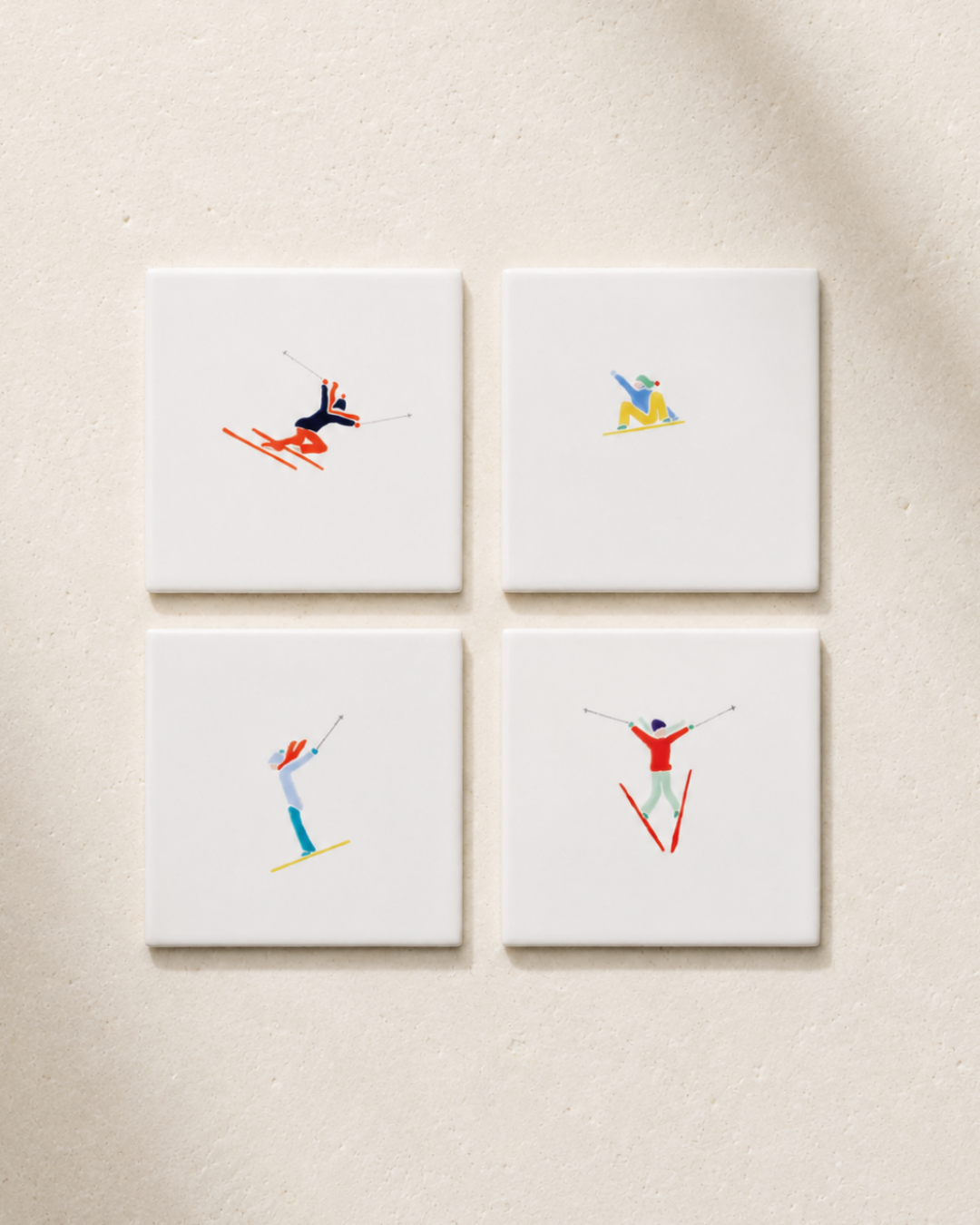 Four coasters with skier illustrations on a beige surface
