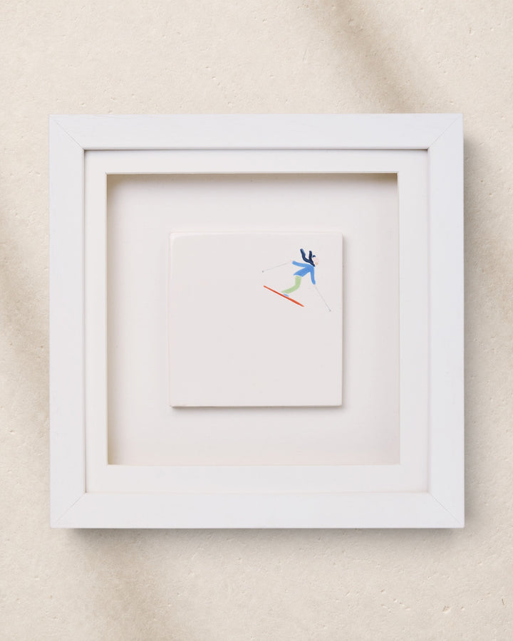 White framed artwork with a small skier figure drawing on a beige background