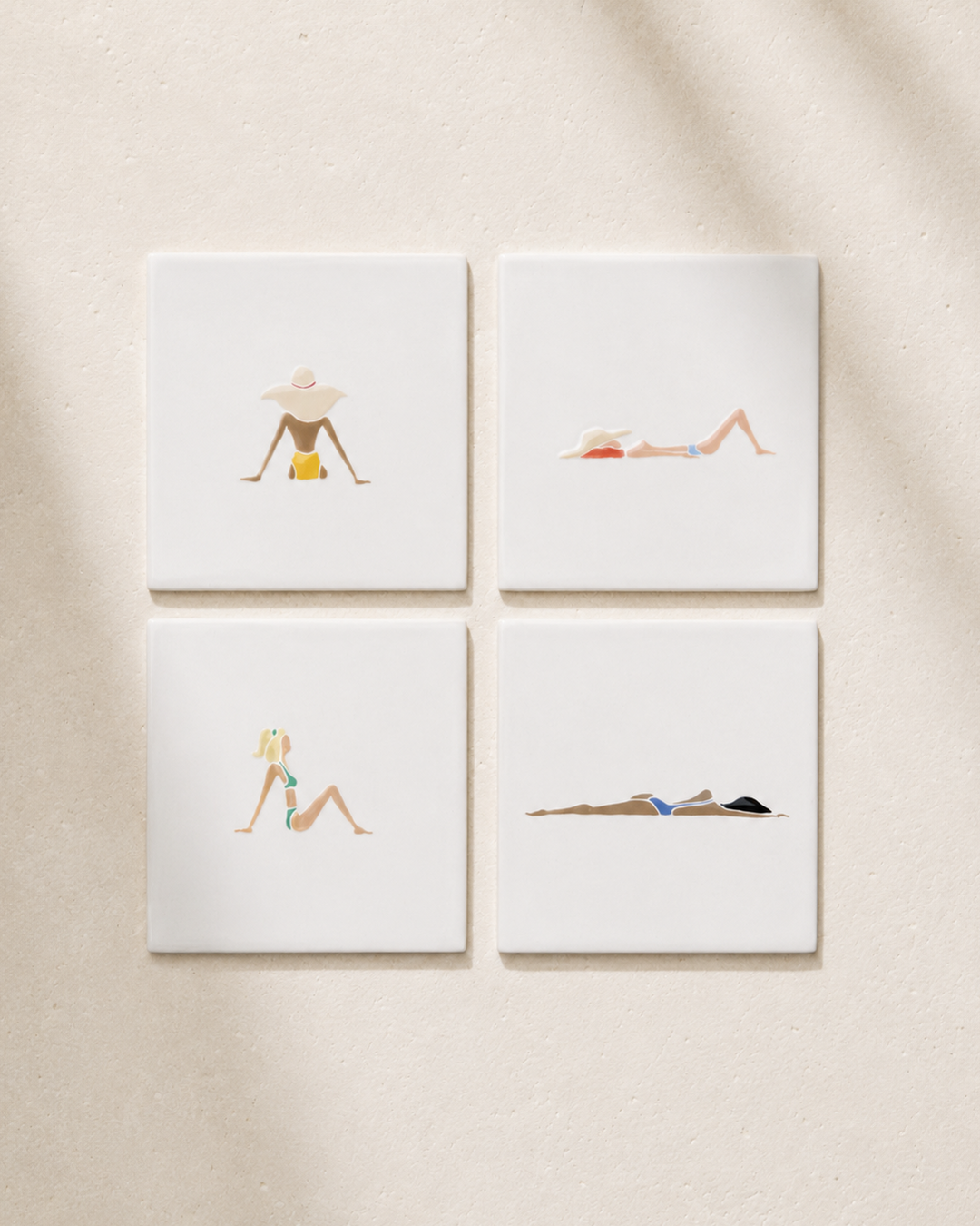 Four coasters with illustrations of women in swimsuits on a beige wall.