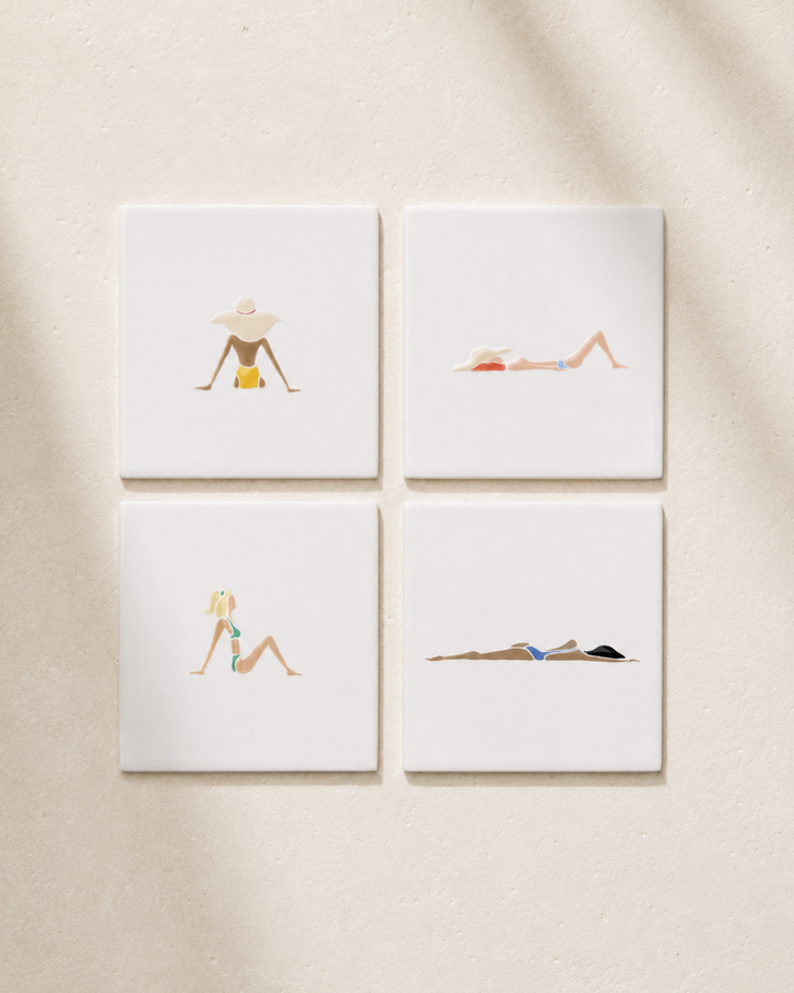 Four coasters with illustrations of women in swimsuits on a beige wall.