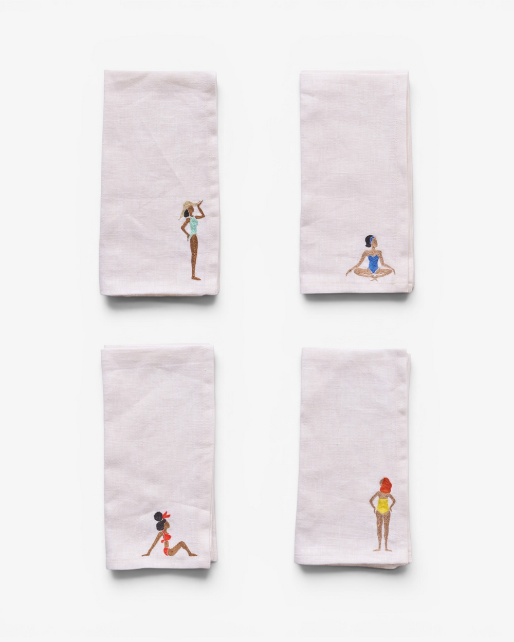 Four embroidered napkins with different designs on a white background