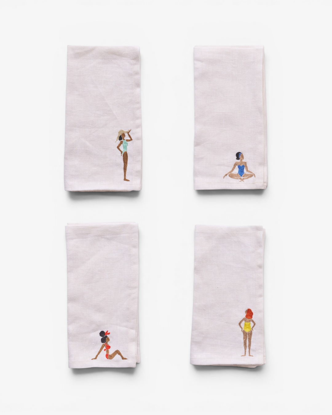 Four embroidered napkins with different designs on a white background
