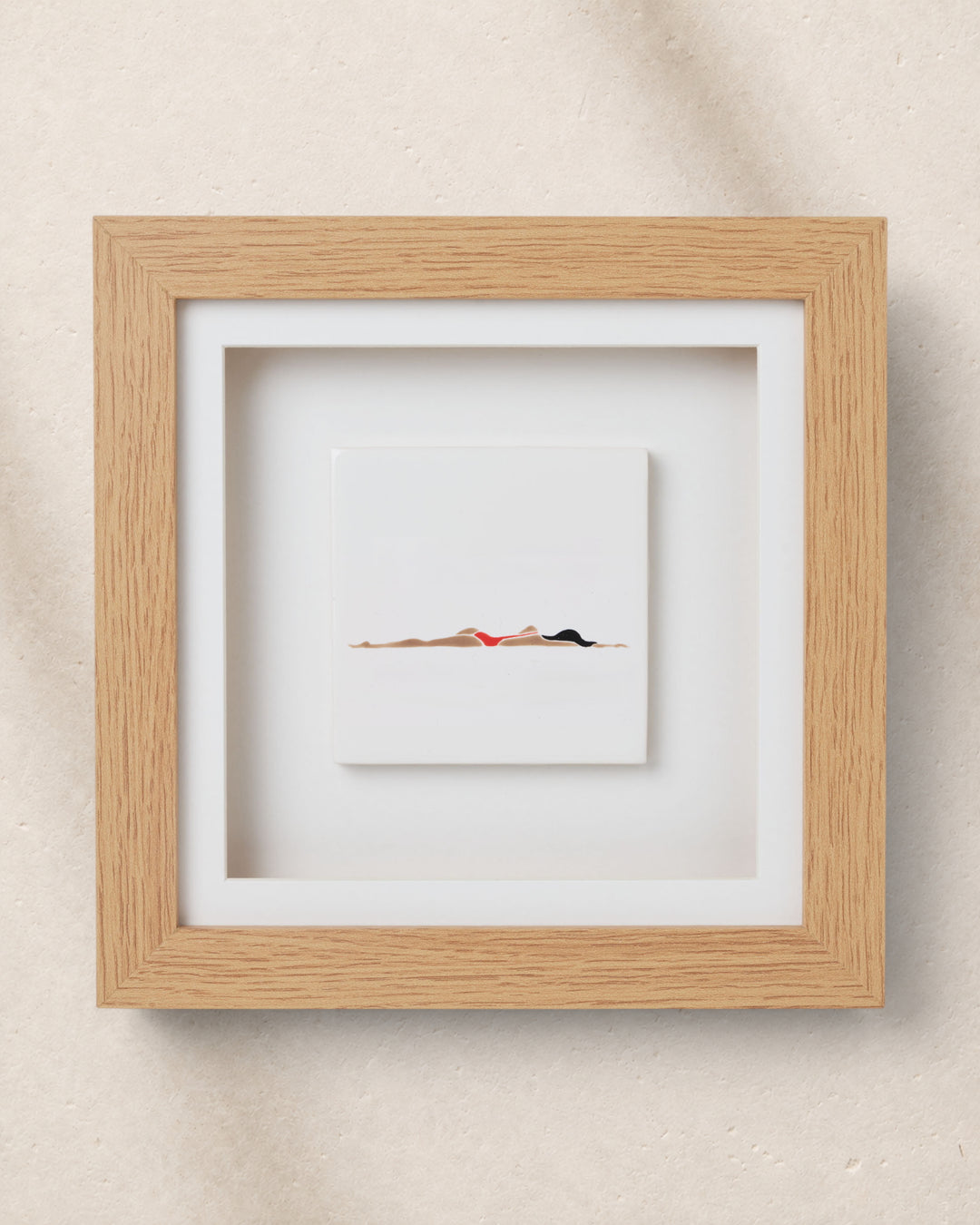 Framed artwork of a swimmer in a minimalistic style on a beige wall.