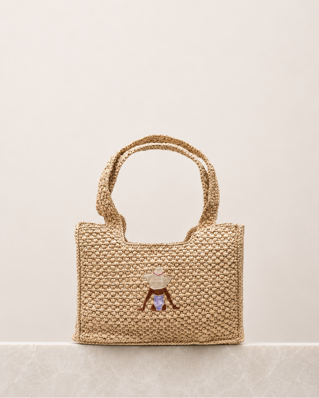 Woven handbag with a decorative charm on a beige background