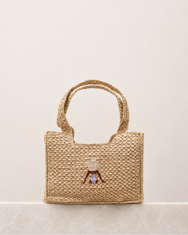 Woven handbag with a decorative charm on a beige background