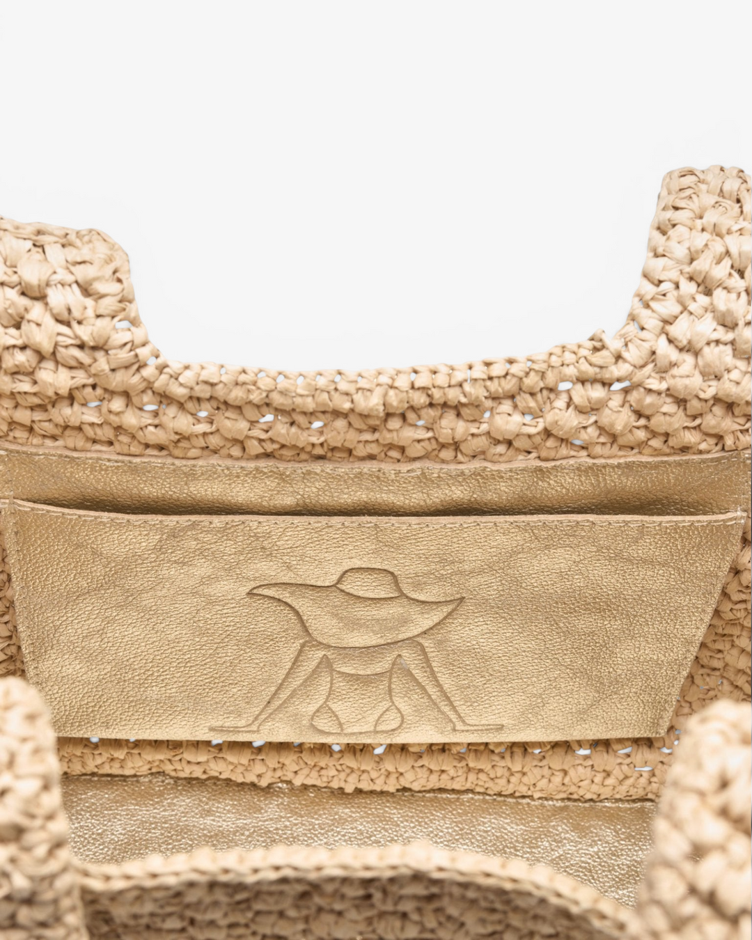 Close-up of a textured beige handbag with a brand logo on a light background