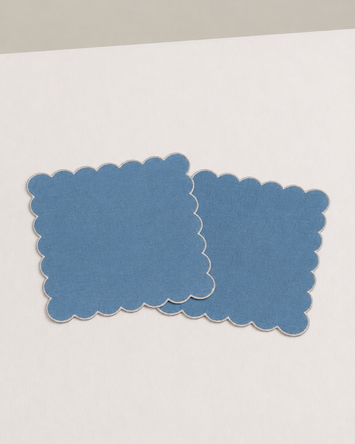 Two blue scalloped napkins on a white surface
