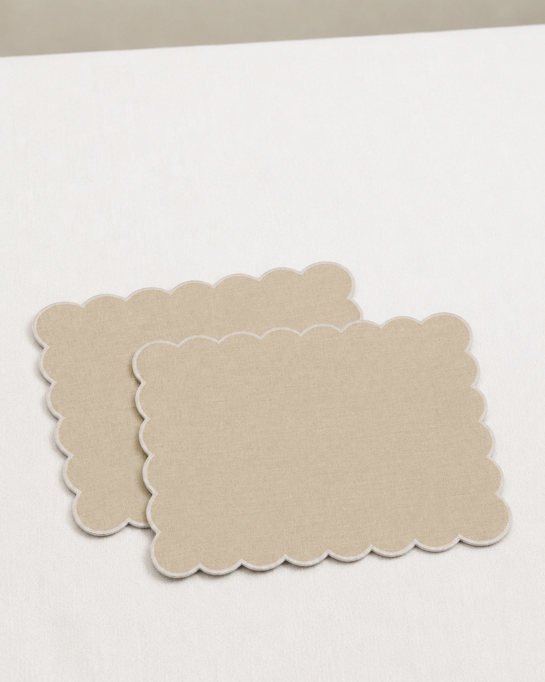 Two beige placemats on a white surface
