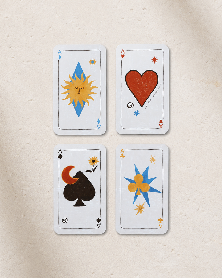 Four playing cards with unique designs on a beige surface
