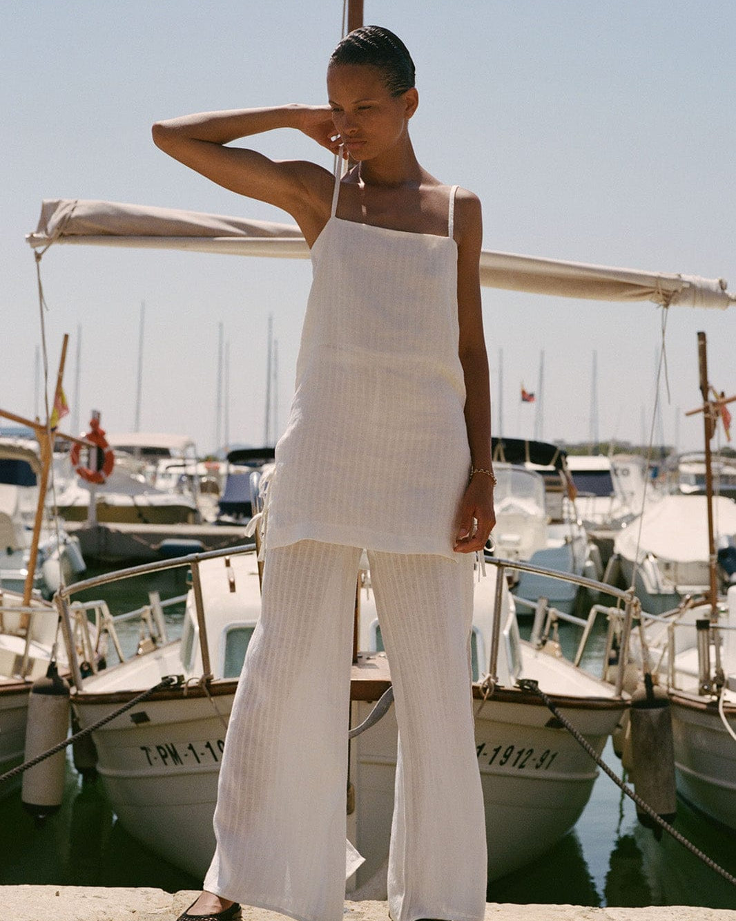 Woman in a white outfit standing by boats in a marina