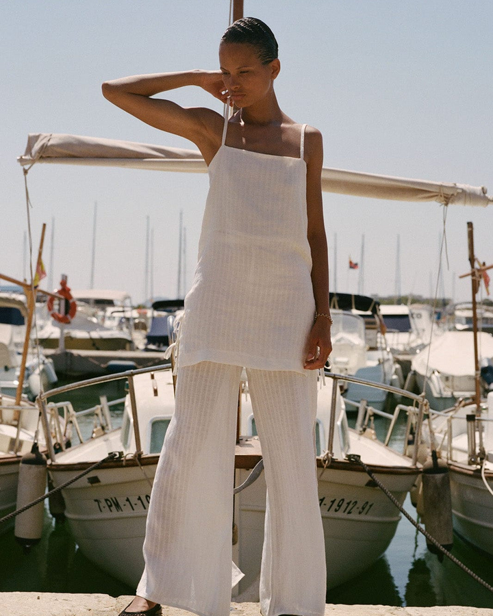Woman in a white outfit standing by boats in a marina