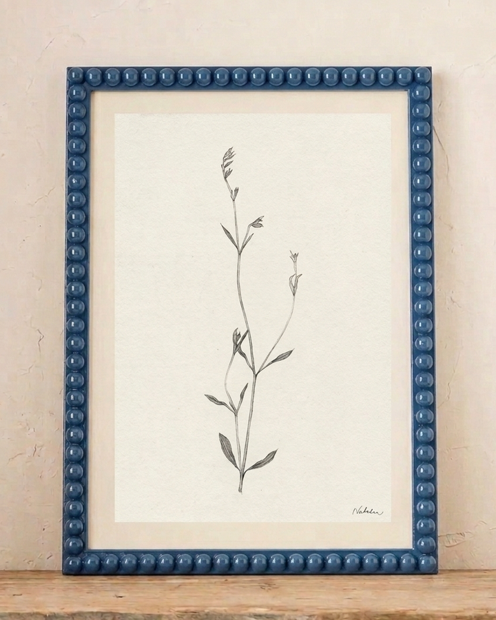 Blue lacquered bobbin photo fame with botanical print on a neutral background