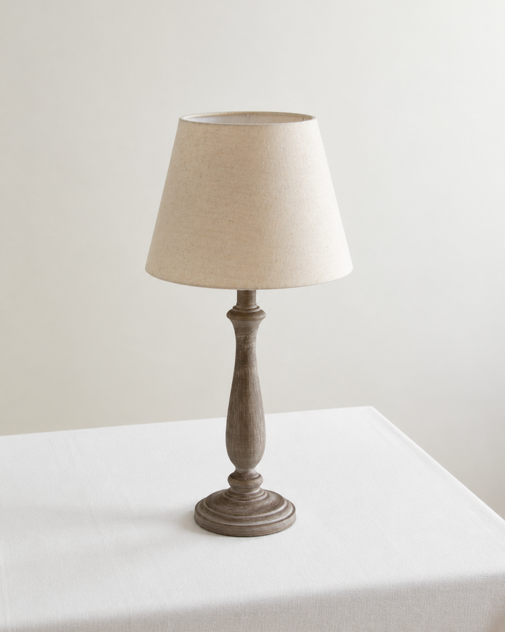 Table lamp with a beige shade on a white surface against a light gray background