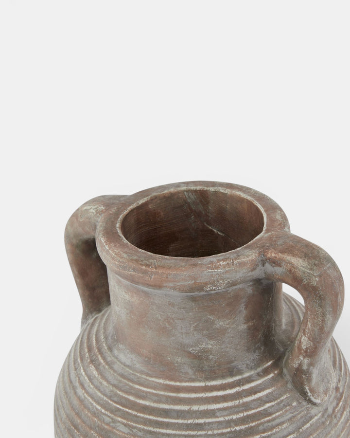 Terracotta vase with handles on a light gray background