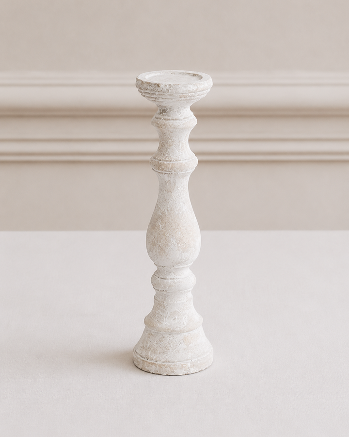 White candle holder on a white surface with a neutral background