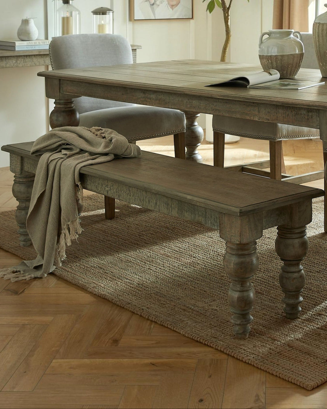 Byretto Laurel rectangular wooden bench with turned legs and a draped linen throw in a rustic dining room setting.