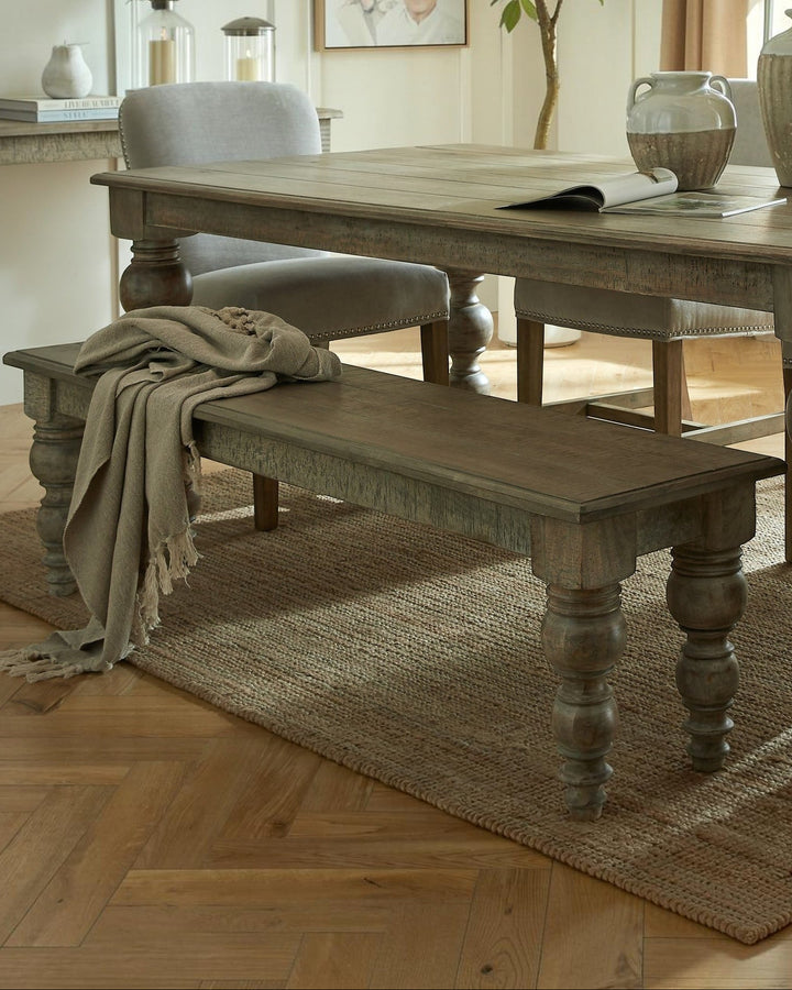 Byretto Laurel rectangular wooden bench with turned legs and a draped linen throw in a rustic dining room setting.