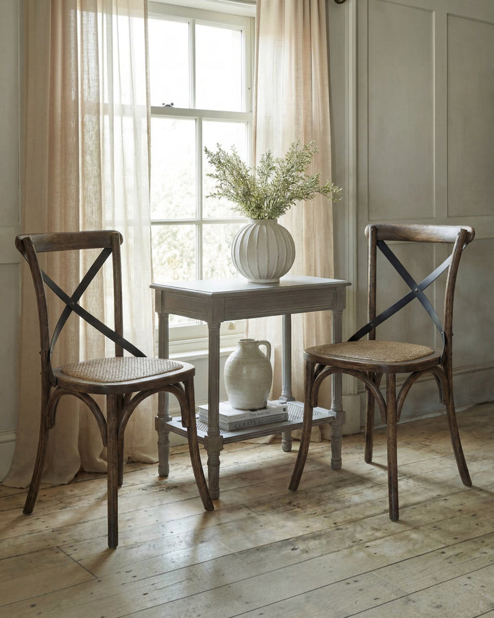 Two Byretto Melrose dining chairs with elm wood cross-back frames and woven rush seats in a bright living room.