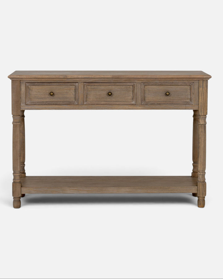 Byretto Mercer console table in a rustic wood finish with three drawers, turned legs, and an open lower shelf.