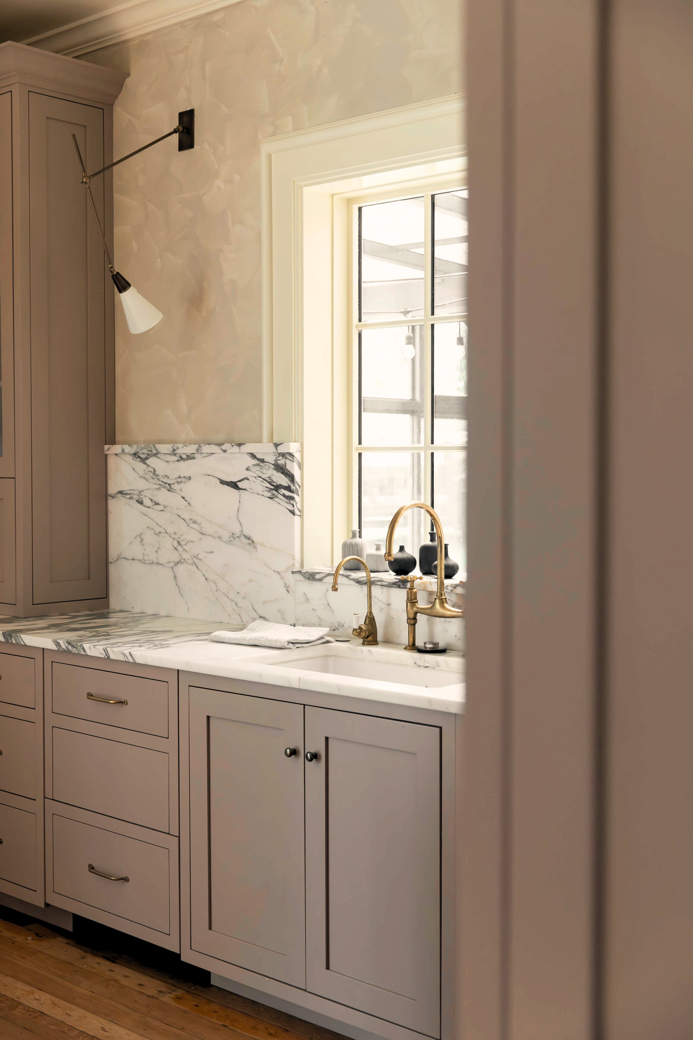 Kitchen with marble backsplash, gold fixtures, and wooden cabinets.