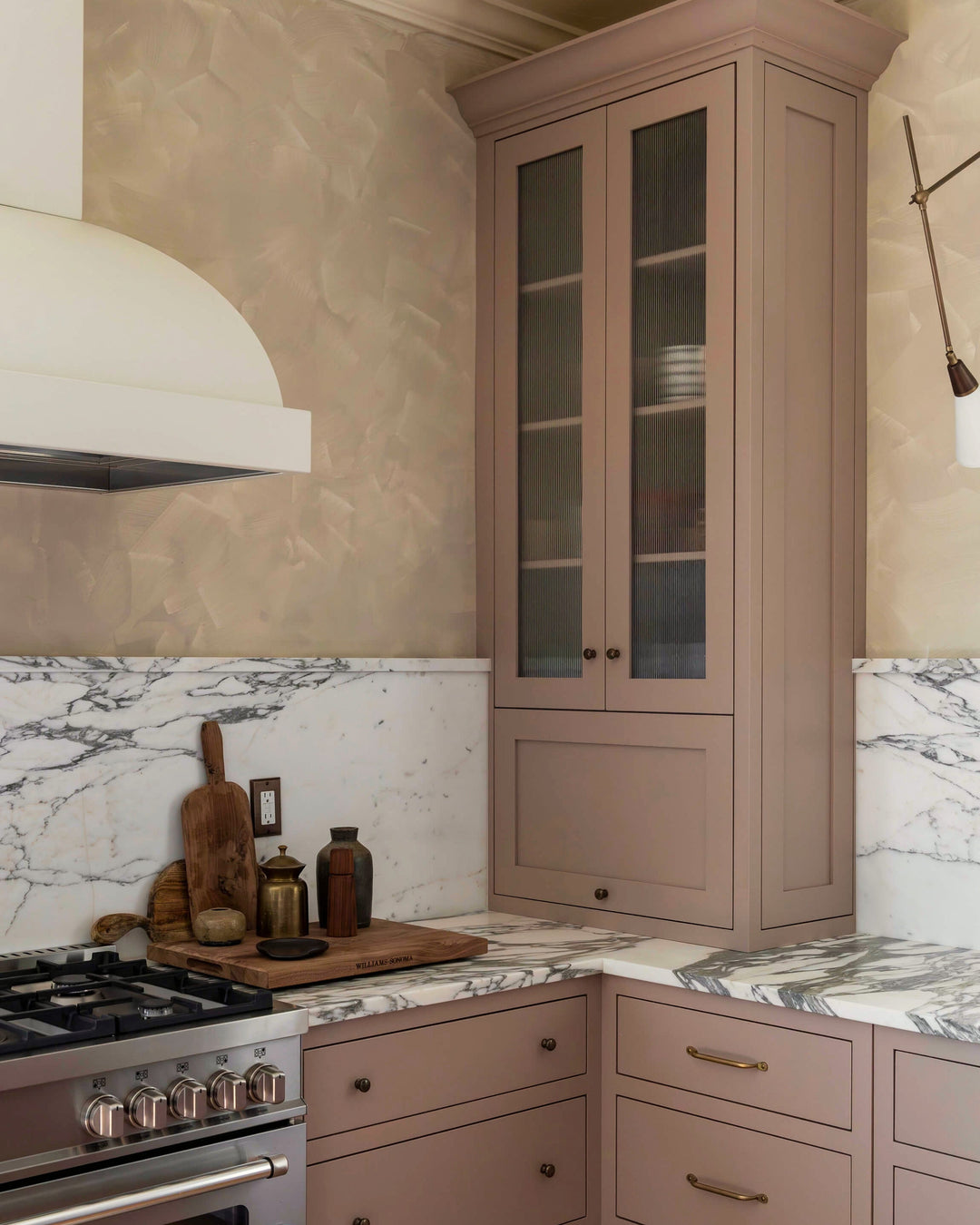 Pink kitchen with cabinets and stove and marble countertops