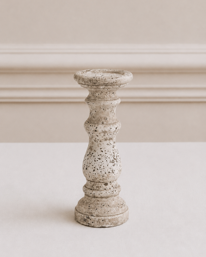 Speckled gray candle holder on a white surface with a neutral background