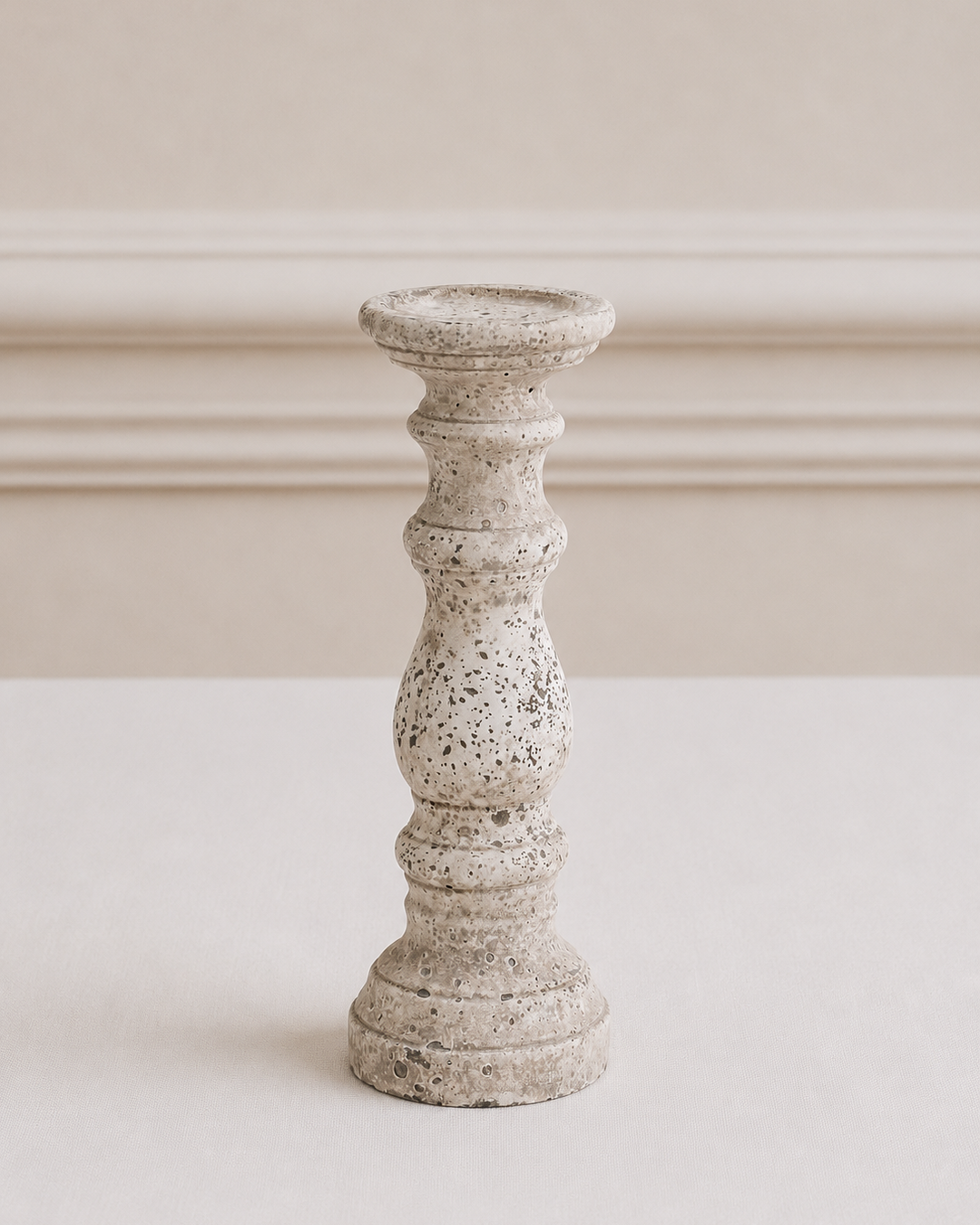 Speckled gray candle holder on a white surface with a neutral background