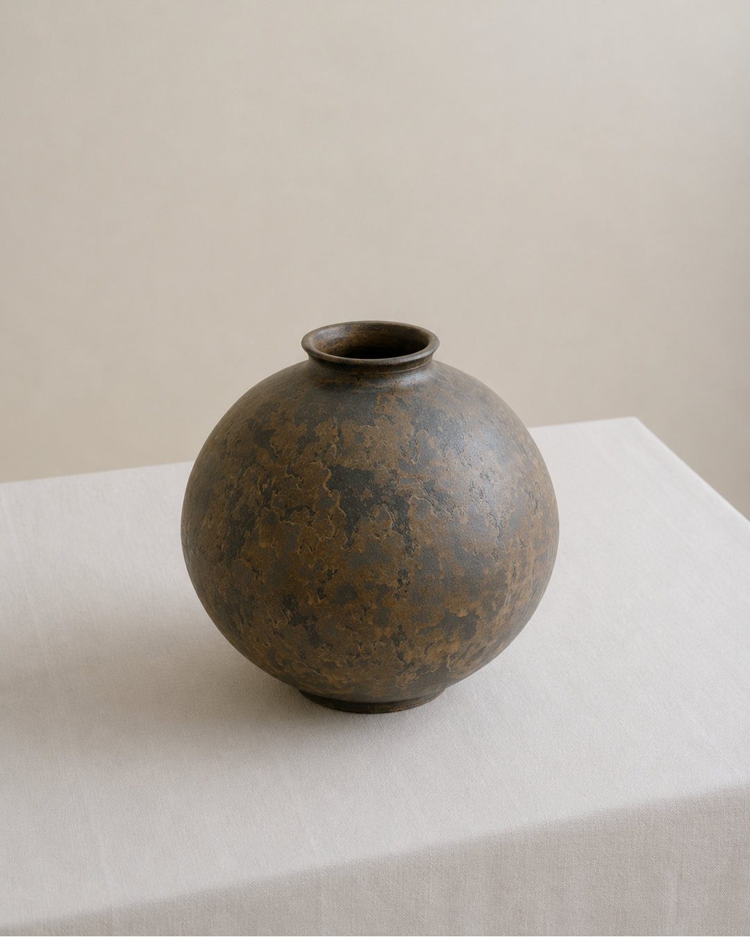Bronze vase on a white surface with a beige background