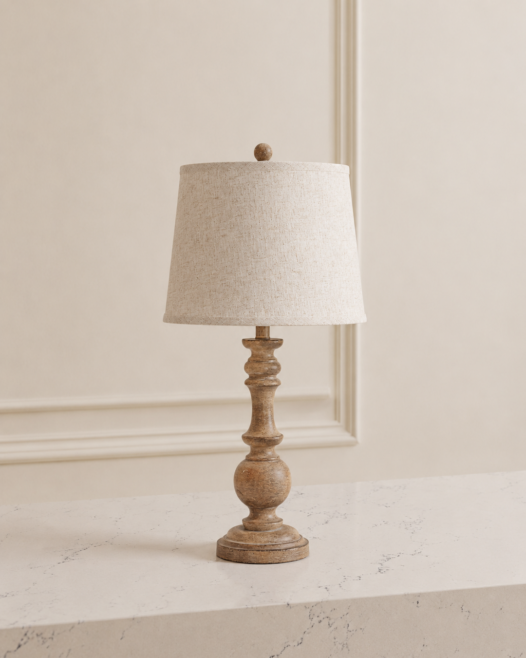 Table lamp with wooden base and beige lampshade on a marble surface.