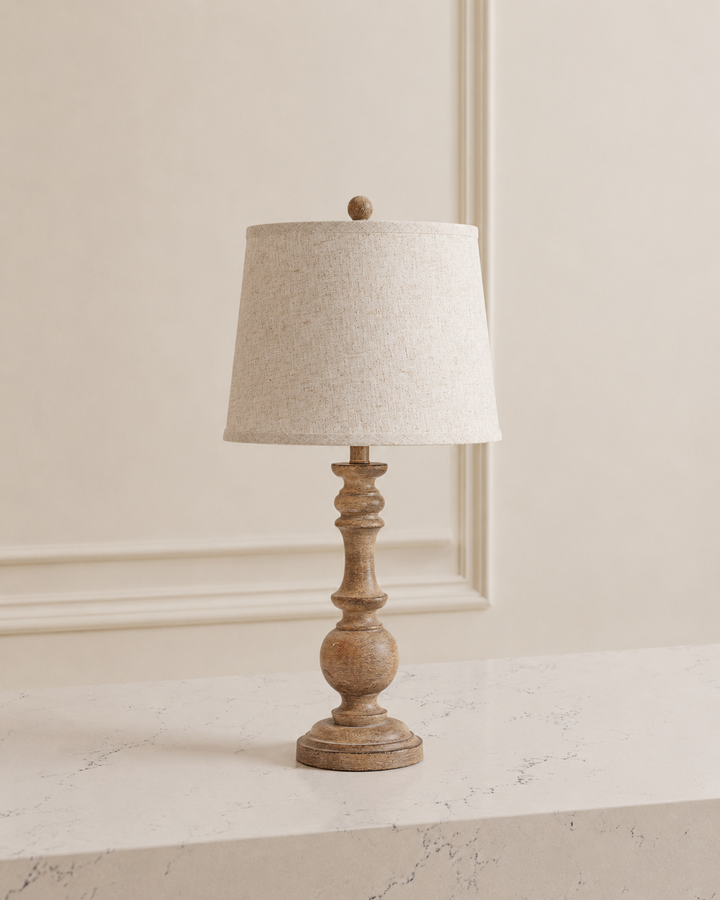 Table lamp with wooden base and beige lampshade on a marble surface.