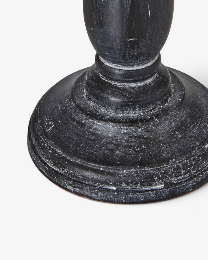 Close-up of a dark wooden lamp pedestal on a white background
