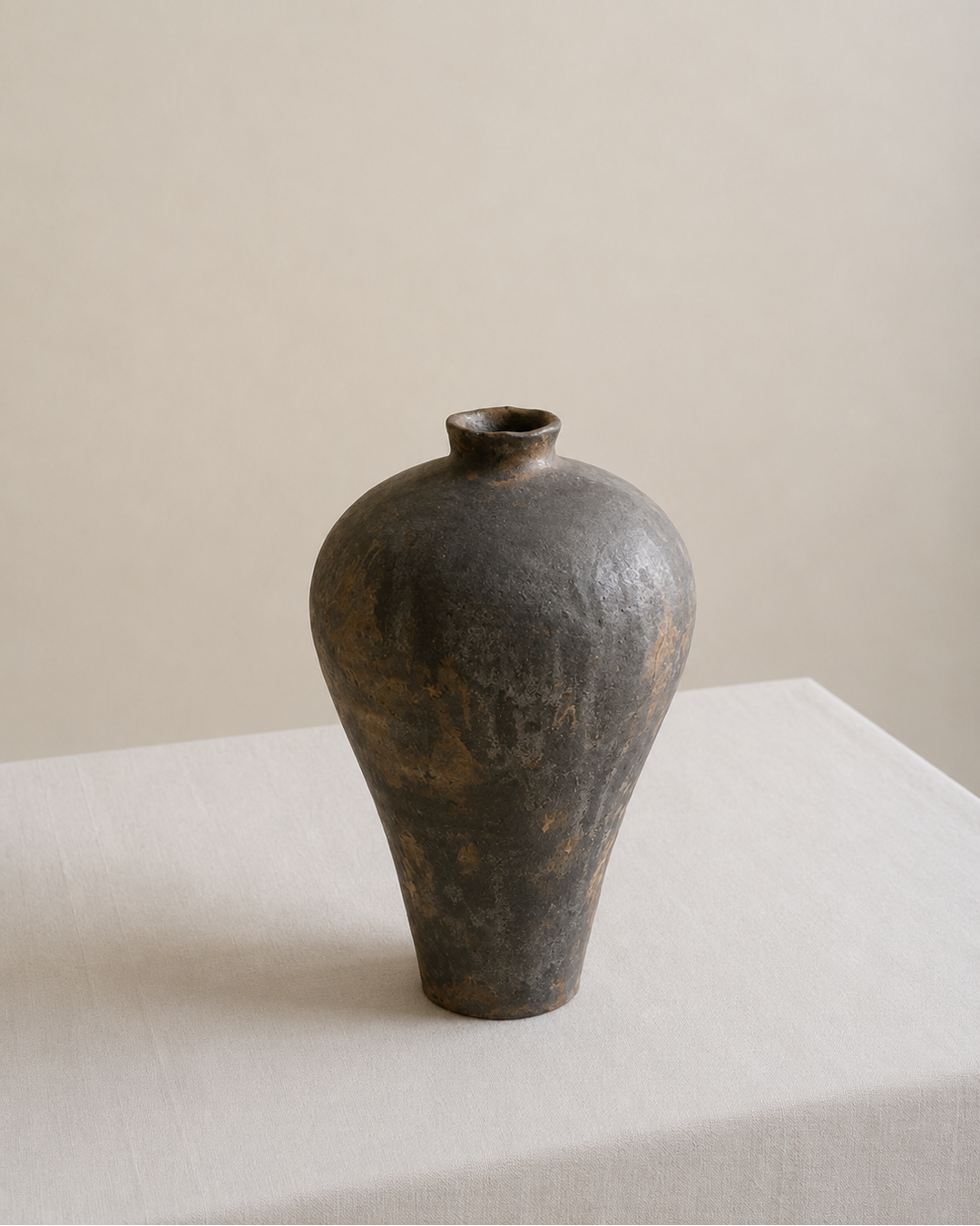 Dark brown ceramic vase on a light surface with a beige background