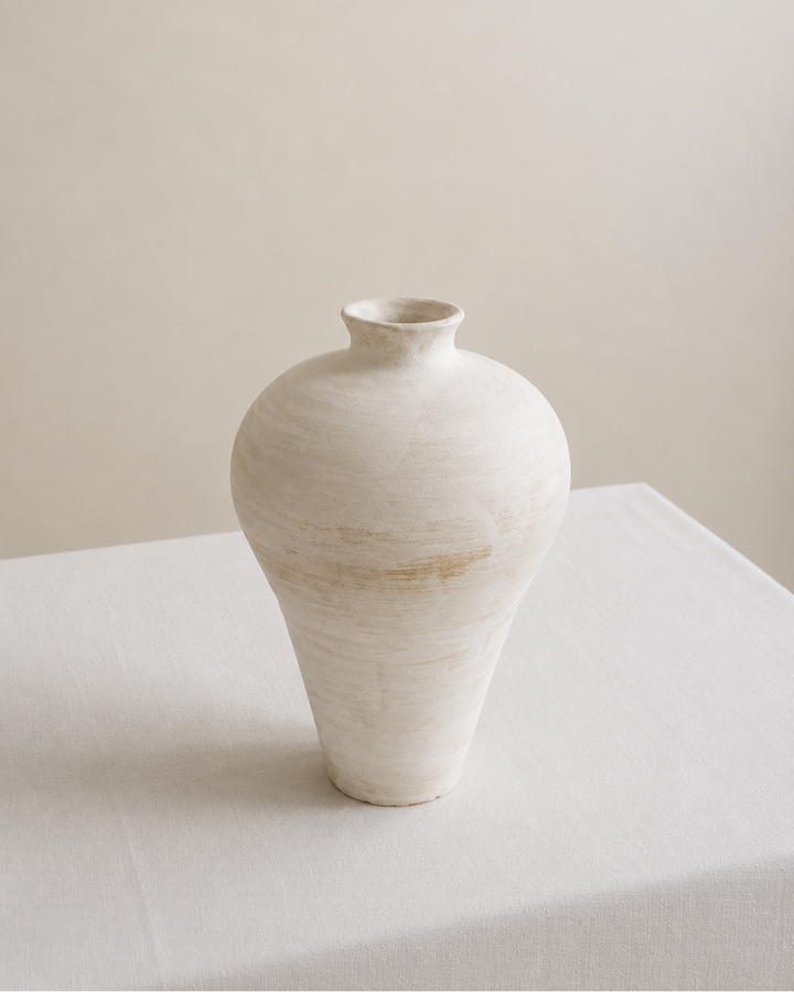 White ceramic vase on a light surface with a neutral background