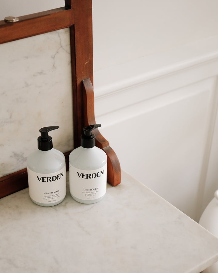 Two Verden bottles on a marble surface with a wooden frame in the background.