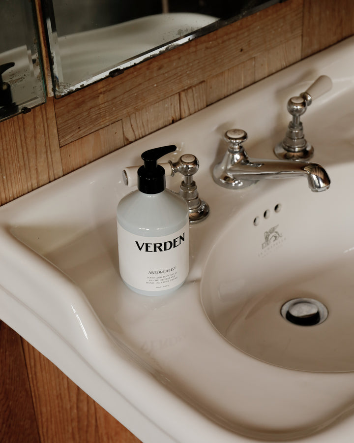 Verden bottle on a bathroom sink with wooden cabinet and mirror.