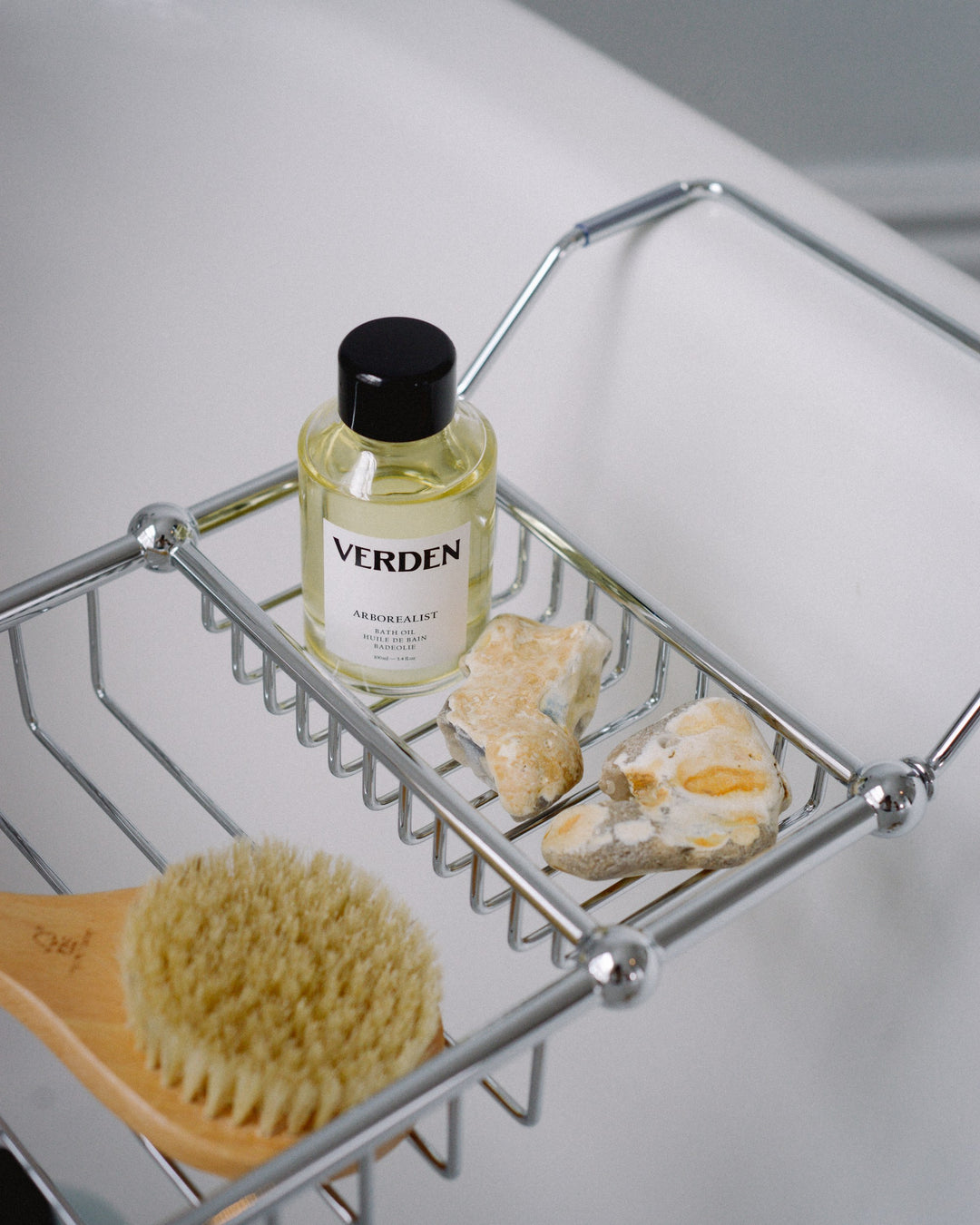 Bottle of Verden product on a metal shelf with a brush and soap.