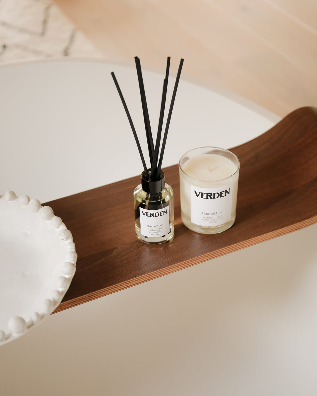 Verden diffuser and candle on a wooden shelf with a neutral background