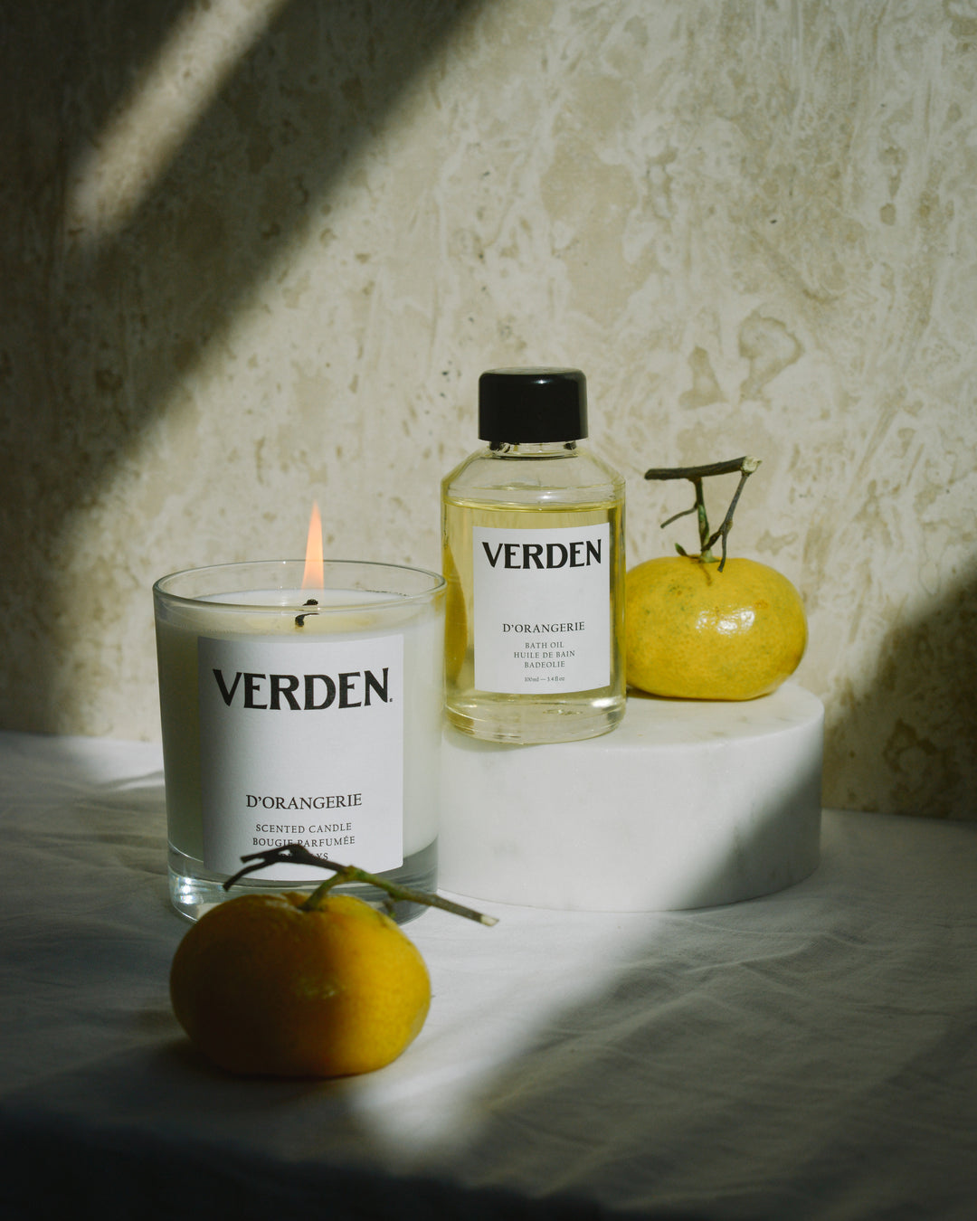 Verden candle and bottle on a textured surface with oranges