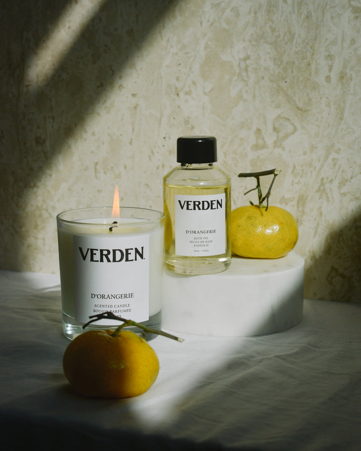Verden candle and bottle on a textured surface with oranges