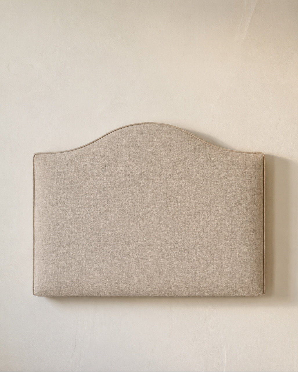 Beige upholstered headboard against a plain wall