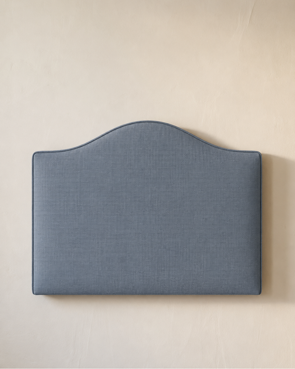Dark blue upholstered headboard on a beige wall
