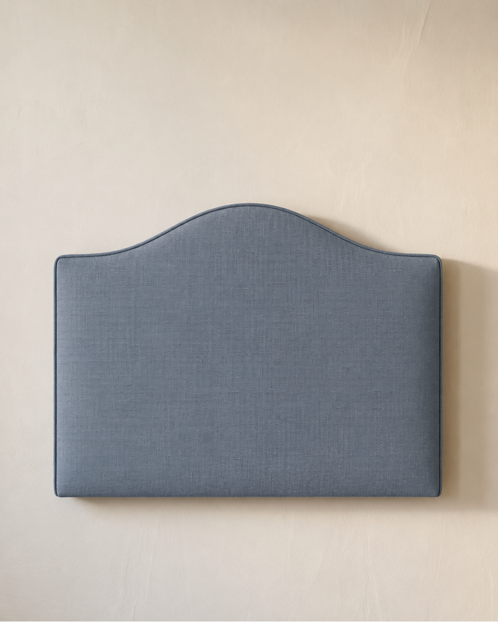Dark blue upholstered headboard on a beige wall