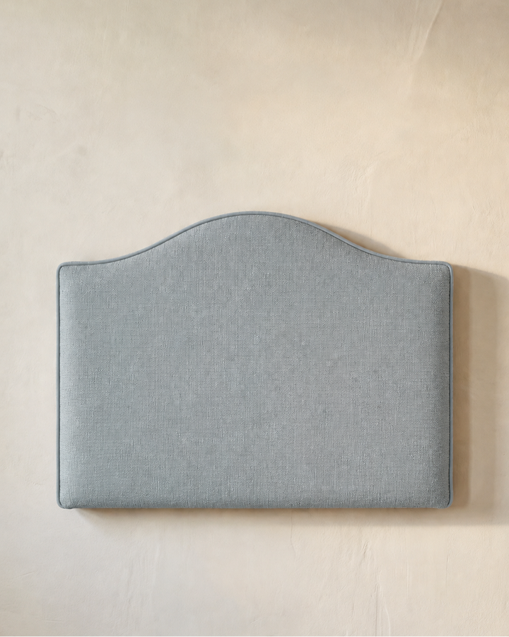Light blue upholstered headboard on a beige wall