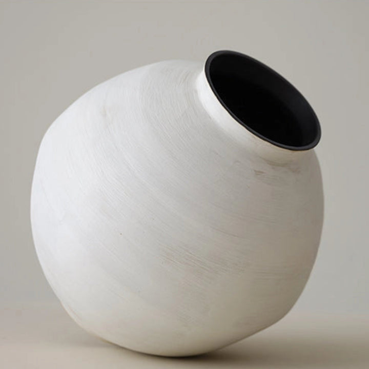 White ceramic vase with black interior on a neutral background