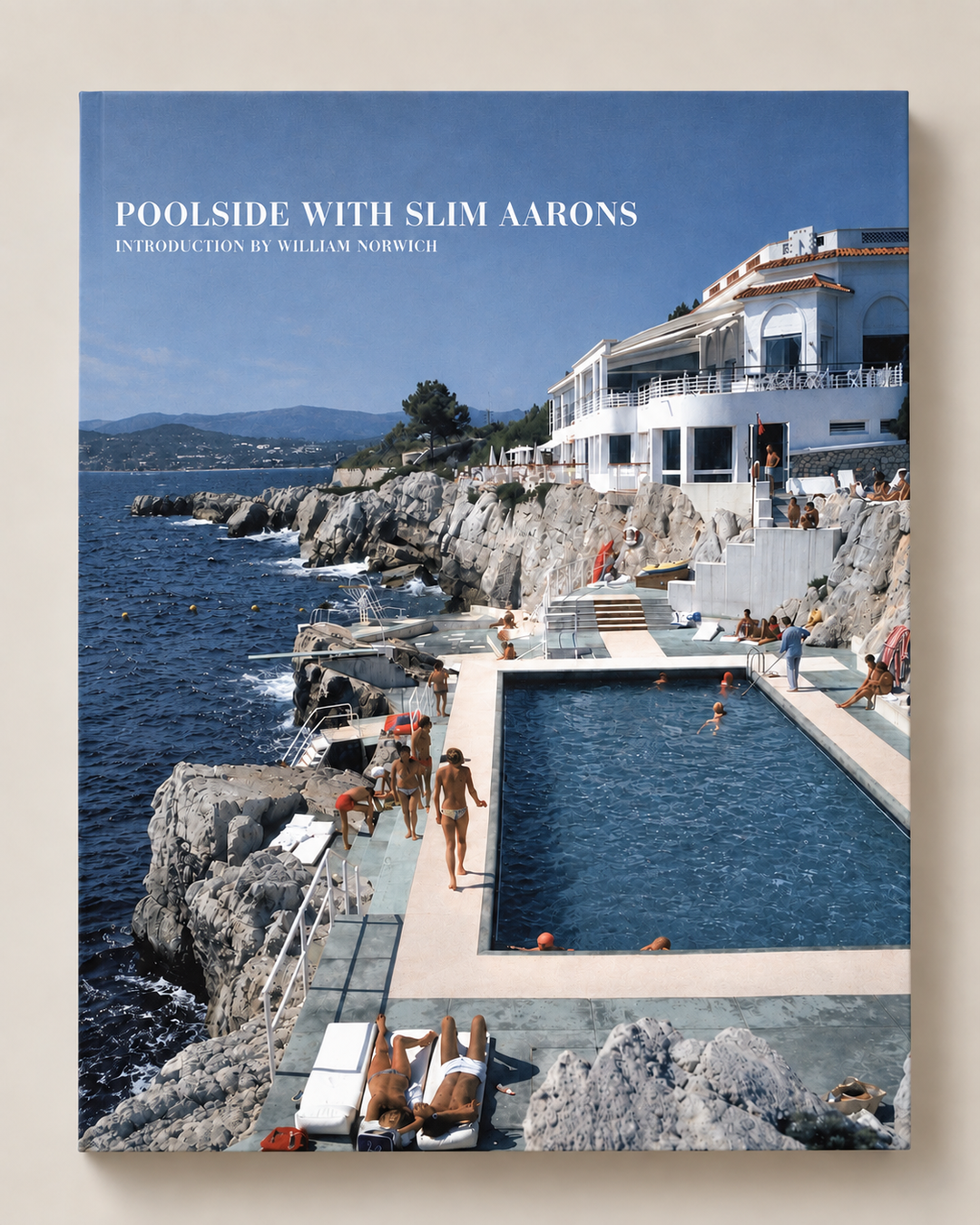 A hardcover book titled 'POOLSIDE WITH SLIM AARONS' by William Norfield, featuring a cover photograph of a coastal swimming pool scene with people, rocks, and blue sky.