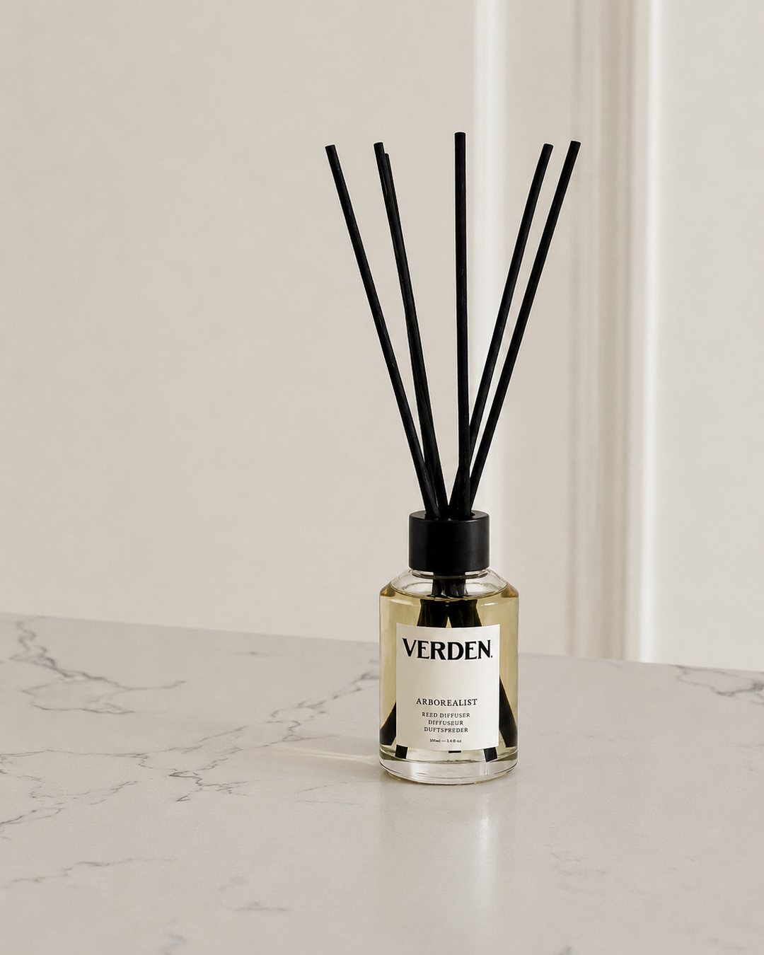 Diffuser bottle with black sticks on a marble surface