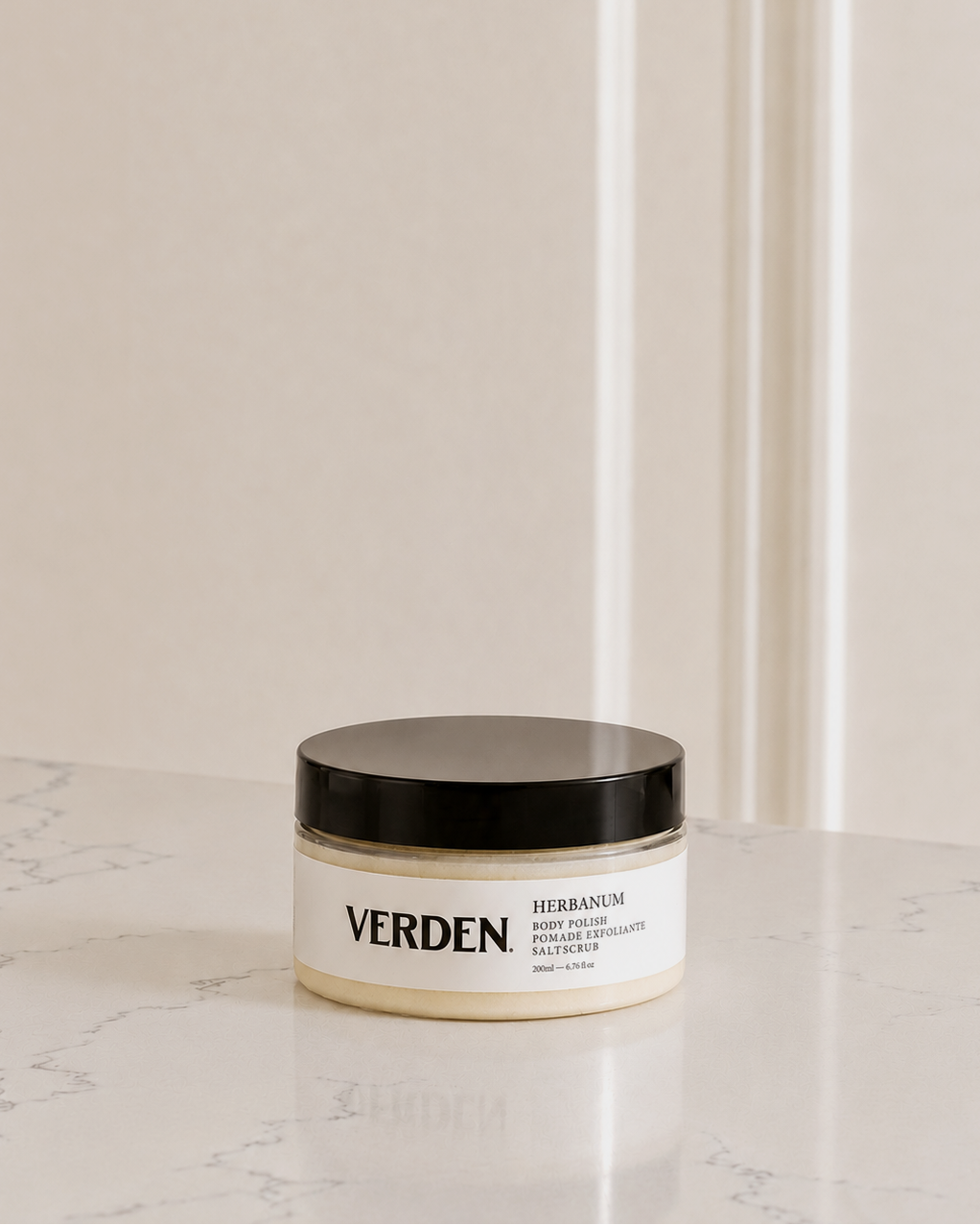 Jar of Verden Herbanum body scrub on a marble surface with a neutral background