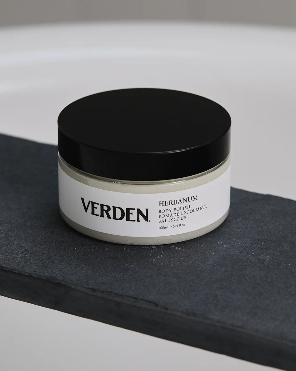 Verden herbanum body polish jar on a black surface